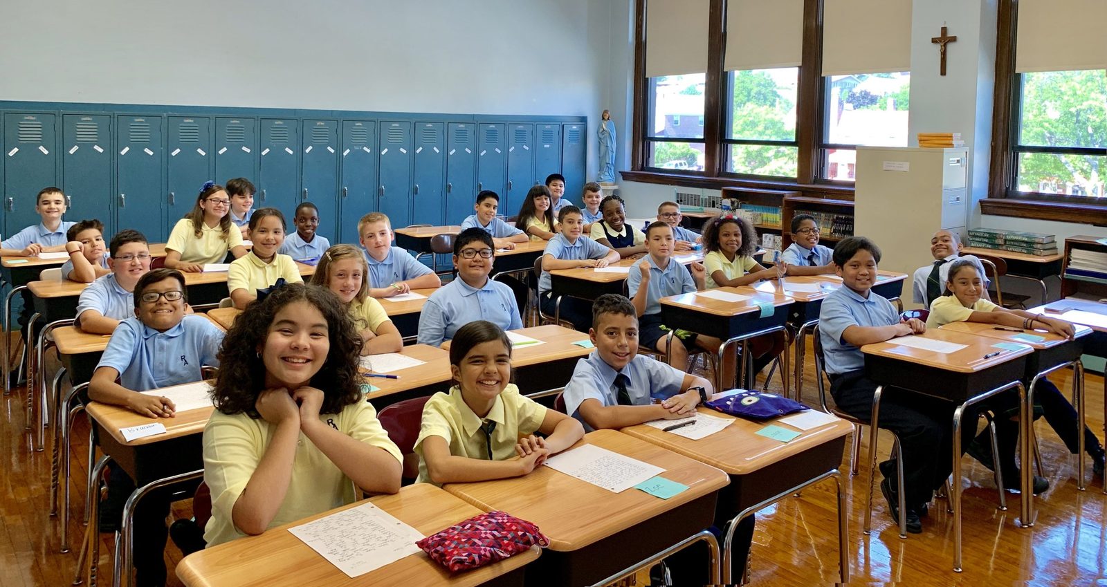 Smiling Catholic school students seated at their desks in a classroom
